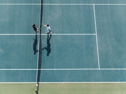 Aerial view of two young man shaking hands on hard court. Tennis players shaking hands over the net after the match.