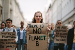 Group of students on the streets demonstrating against climate change. People protesting for problem in ecology, environment, global warming, industrial influence, climate emergency.