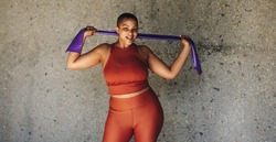 Plus size woman working out with resistance band. Healthy female in fitness attire exercising outdoors.