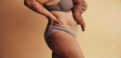 Mid section of plus size woman with baby. Body positive woman postpartum. Mother with visible postpartum body marks with baby.