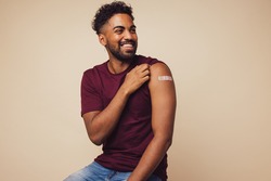 Man smiling after receiving vaccination. Man showing his arm after receiving a vaccine.