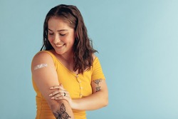 Woman looking at her arm with band-aid after receiving vaccine dose. Woman getting vaccination. 