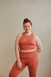 Female in fitness wear standing after workout. Fit plus size woman looking at camera and smiling.