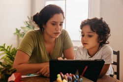 Supportive mother watching an online tutorial with her son. Mother and son going through educational content on a digital tablet. Loving single mother home schooling her young son.