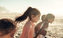 Group of energetic young kids running and having fun together at the beach. Happy little children enjoying their summer vacation at a sunny beach.