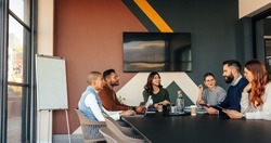 Group of multicultural businesspeople having a meeting in a boardroom. Happy businesspeople having a discussion during their morning briefing. Young entrepreneurs collaborating in a modern office.
