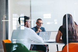 Group of businesspeople having a discussion in a meeting room. Experienced mature businessman leading a meeting in a modern office. Group of creative businesspeople working as a team.
