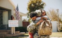 Emotional family reunion. Military dad embracing his children after returning home from the army. American soldier receiving a warm welcome from his family after serving in the military.
