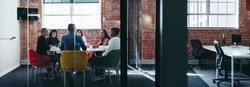 Team of businesspeople having a discussion during a meeting. Group of creative businesspeople attending their morning briefing in an office. Businesspeople working together as a team.