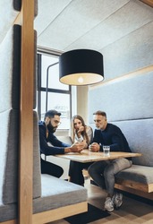 Group of businesspeople working in a co-working space. Three business colleagues using a smartphone during a discussion. Team of diverse entrepreneurs collaborating on a new project.