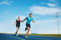 Shot of professional male athletes passing over the baton while running on the track. Athletes practicing relay race on racetrack.