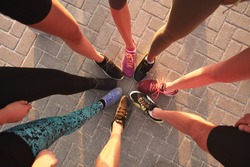 Legs of athletes wearing sports shoes in a circle. Top view of runners standing together.
