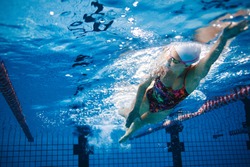 Underwater shot of fit swimmer training in the pool. Female swimmer inside swimming pool.