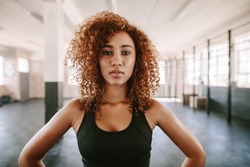 Portrait of beautiful afro american female with curly hair in gym. African fitness woman at healthclub.