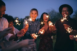 Group of friends enjoying out with sparklers. Young men and women enjoying with fireworks.