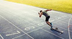 Rear view of an athlete starting his sprint on an all-weather running track. Runner using starting block to start his run on race track.