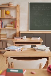Vertical background image of wooden school desks in row facing blackboard in empty classroom