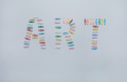 Colorful art inscription made of paper clips on gray background, office creativity concept