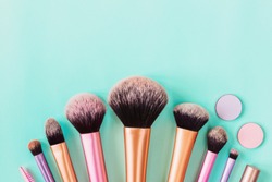 Makeup brushes on aqua colored background. Top view, flat lay, copy space