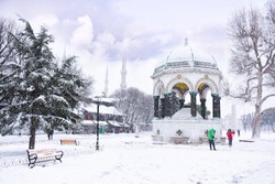 German Fountain in old Hippodrome, Istanbul, Turkey in winter day with snow, one tourist group walk around.