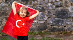 Portrait of happy little kid. Cute baby with Turkish flag t-shirt. Toddler hold Turkish flag in hand. Patriotic holiday. Adorable child celebrates national holidays. Copy space for text.