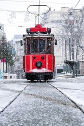 Red nostalgic tram is moving on the Istiklal street in Beyoglu, Taksim. Winter day with snow. Cold snowy weather in Turkey. Flu season.                                  