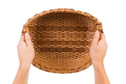 Human hands hold a wicker basket. Wicker basket made of willow branches and shavings. Isolated over white background. Close-up.
