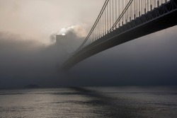 Bridge hidden in the fog at sunrise. The Verrazano-Narrows Bridge is a double-decked suspension bridge that connects the New York City boroughs of Staten Island and Brooklyn
