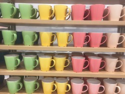 Colorful mugs on shelf in retailer gift shop.