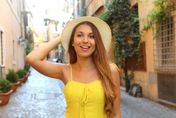 Attractive fashion girl in Trastevere, Rome. Beautiful smiling woman with yellow dress and hat walks through the streets of Rome, Italy.