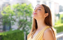 Relaxed young woman breathing fresh air on balcony in the morning