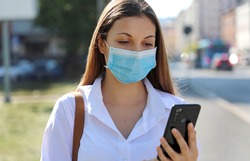 COVID-19 Mobile Application Young Woman Wearing Surgical Mask Using Smart Phone App in City Street to Aid Contact Tracing in Response to the 2019-20 Coronavirus Pandemic