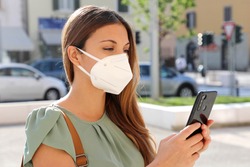 COVID-19 Mobile Application Young Woman Wearing KN95 FFP2 Mask Using Smart Phone App in City Street to Aid Contact Tracing and Self Diagnostic in Response to Coronavirus Disease 2019