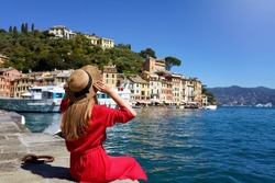 Visiting Portofino, Italy. Travel tourist girl on vacation sitting in Portofino harbour. Attractive young romantic woman enjoying view of Portofino picturesque village in Italy.