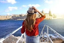 Tourism in Europe. Back view of traveler girl walking on stairs enjoying view of Valletta city, Malta. Young female tourist visiting southern Europe.