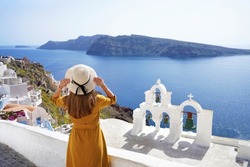 Tourism in Europe. Back view of young woman looking stunning landscape in the picturesque village of Oia, Santorini Island, Greece.