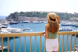 Vacation in Monaco. Back view of young woman in Monte-Carlo looking cityscape and harbor in the Principality of Monaco.