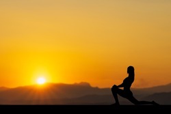 Silhouette of woman practicing warrior yoga at sunset, healthy concept.