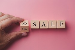Sale word no to yes. Hand turns a dice and changes the word no to yes. On sale Cubes dice with Sale Yes or No on wooden background, pink color background.