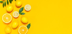 Ripe juicy lemons, orange and green leaves on bright yellow background. Lemon fruit, citrus minimal concept, vitamin C. Creative summer minimalistic background. Flat lay, top view, copy space. 
