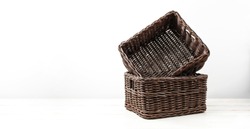 Empty wicker brown rattan basket on a white wooden background and white wall. Natural eco handmade item for home, interior. Home basket. 