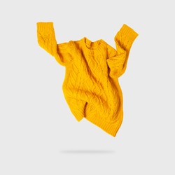 Yellow orange flying women's autumn knitted sweater on light gray background. Creative clothing concept, trendy fall winter cozy sweater pullover jersey. Women's fashion, autumn discounts. Shopping