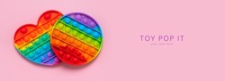 Popular silicone multi-colored anti-stress toy pop it on pink background flat lay top view. Trendy modern sensory children's toy, fidget push pop it