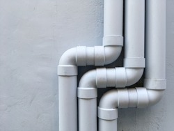 Three drain pipes on the gray wall