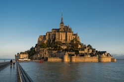 Dramatic sunrise over the famous Mont Saint-Michel, a town located in Normandy west of Paris on the small island near the riverside. Amazing view of French old Gothic architecture.