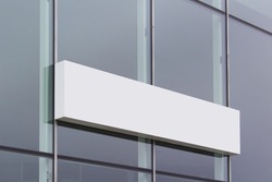 Long white shop banner sign board hanging on glass office building surface.