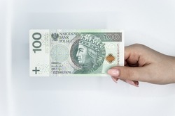 Polish currency held in the hand against a white background