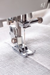 Modern sewing machine presser foot with linen fabric and thread, closeup, copy space. Sewing process clothes, curtains, upholstery. Business, hobby, handmade, zero waste, recycling, repair concept