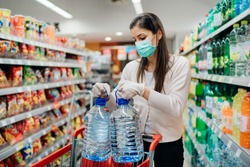 Buyer wearing a protective mask.Shopping during the pandemic.Emergency to buy list.Water supplies shortage.Panic buying during coronavirus outbreak.Preparation for a pandemic quarantine
