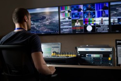 TV engineer at editor in studio. TV editor working with vision mixer in a television broadcast gallery.Man sat at a vision mixing panel in a television studio gallery